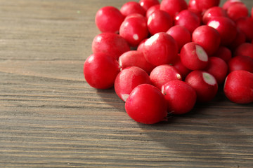 Heap of fresh radishes on wooden table close up background