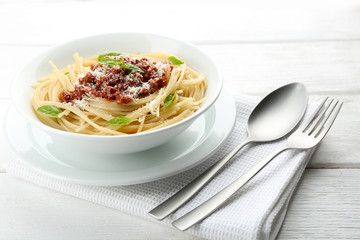 Spaghetti Bolognese with parmesan cheese in white bowl, on color wooden background