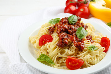 Spaghetti Bolognese on white plate, on color wooden background