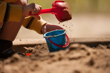 In the sandbox. / Pour sand into the bucket in the sandbox. © zimogljad