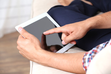 Male hand holding PC tablet on home interior background