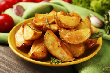 Baked potato wedges on wooden table, closeup