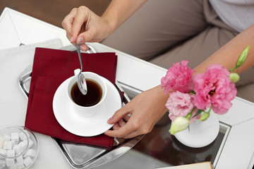Fototapeta na wymiar Female hand holding cup of tea on table close up