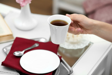 Female hand holding cup of tea in living room