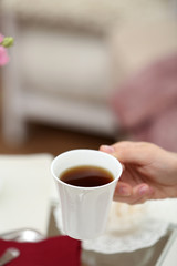 Female hand holding cup of tea in living room