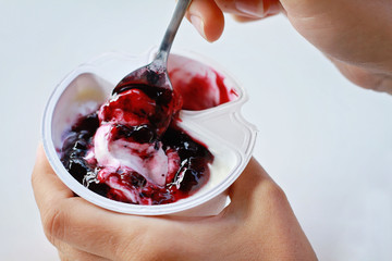 Close up on hands holding yogurt with fruit blueberry jam. healthy breakfast, diet food