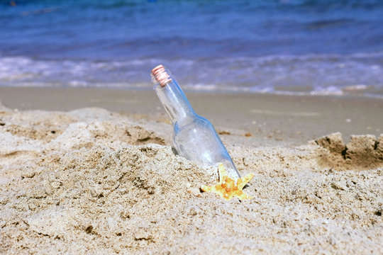 Message in bottle on sand on sea background