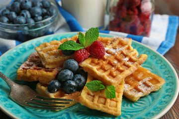 Sweet homemade waffles with forest berries and sauce on table background