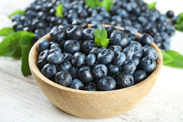 Tasty ripe blueberries with mint in bowl on table close up