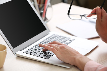 Woman using laptop on workplace close up