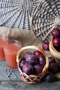 Delicious plum juice with fruits on wicker background
