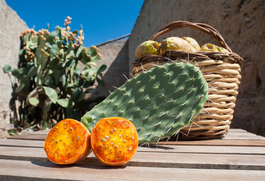 Prickly pears and wicker basket full of just picked fruits near an old country house