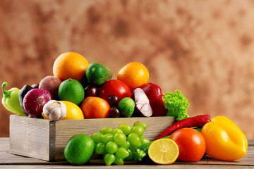 Fototapeta na wymiar Heap of fresh fruits and vegetables in crate on wooden table close up