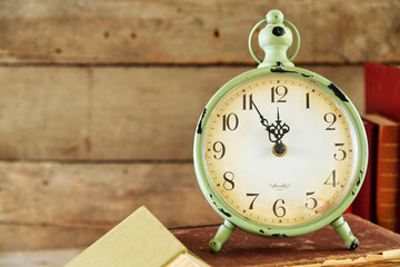 Clock and vintage books, on rustic wooden background