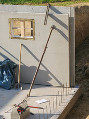 Bau eines Fertigkellers mit einer Betonwand mit Aussparung für Kellerfenster