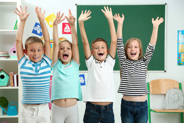 Fototapeta premium Portrait of happy classmates looking at camera in classroom