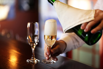 Bartender pouring champagne into glass, close-up