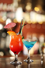 Glasses of cocktails on bar background