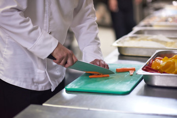 chef in hotel kitchen  slice  vegetables with knife