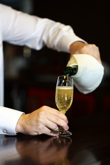 Bartender pouring champagne into glass, close-up