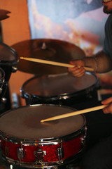 Drummer with wooden sticks and drums on dark background