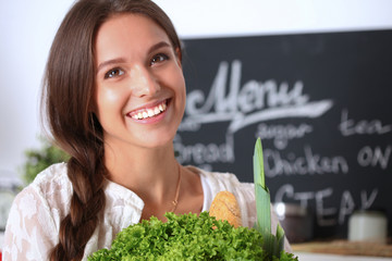 Young woman holding grocery shopping bag with vegetables 