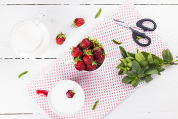 Bowl with strawberry, glass and jug with milk, mint on white woo