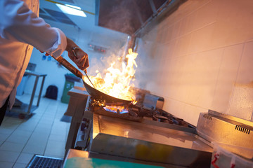 chef in hotel kitchen prepare food with fire