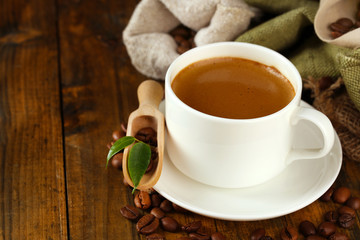 Cup of coffee with beans on table close up