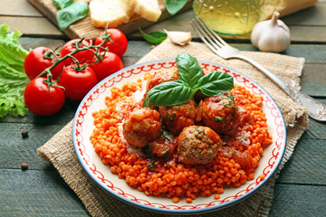 Meat balls with lentil and tomato sauce, wooden spoon on wooden background