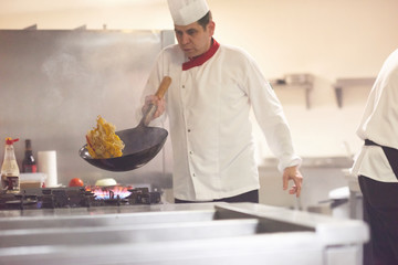 chef in hotel kitchen prepare food with fire