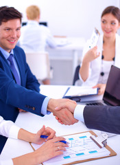 Business people shaking hands, finishing up a meeting, in office