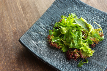Plate of fresh mixed green salad on wooden table close up