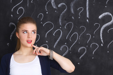 Obraz premium Young girl with question mark on a gray background