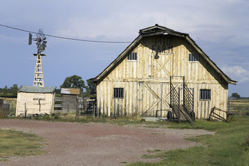 Old yellow barn and windmill in Western Nebraska