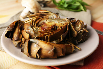 Roasted  artichokes on plate, on color wooden background