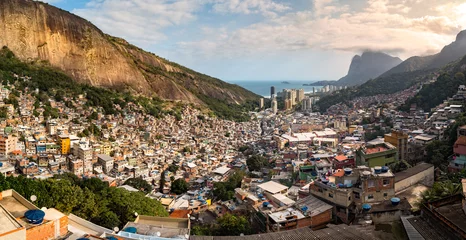 Papier Peint photo Lieux américains Panoramic view of Rio's Rocinha favela, on a sunny afternoon.  Visible in the distance is the South Atlantic Ocean. The high-rise buildings near the coast are condominiums in Sao Conrado