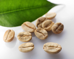 Heap of green coffee beans with leaf isolated on white