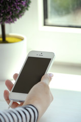 Music smartphone in female hand, on light background