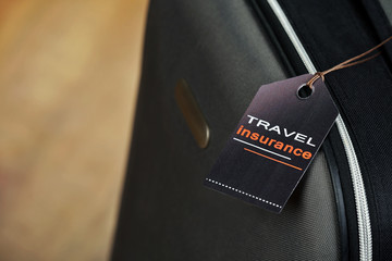 Suitcase with TRAVEL INSURANCE label, closeup