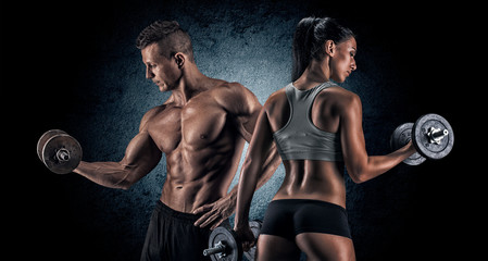 Athletic man and woman with a dumbells. - obrazy, fototapety, plakaty