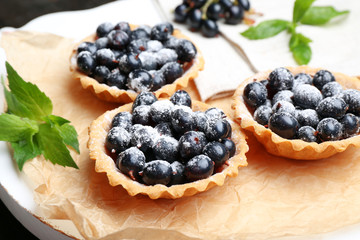 Delicious crispy tarts with black currants on parchment, closeup
