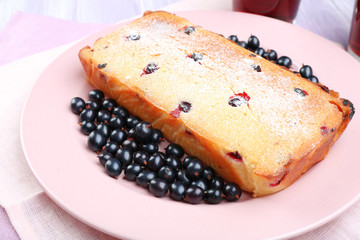 Freshly baked cake with black currants in pink plate, closeup