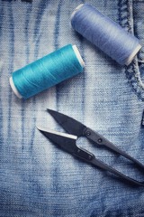 Bobbins threads with scissors on jeans