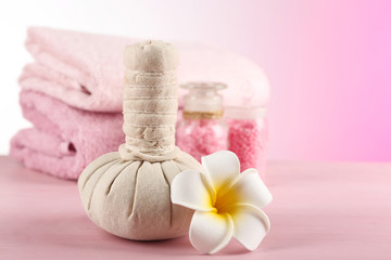 Massage bags with spa treatment and flowers on wooden table, on light background