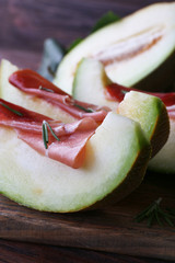 Melon with prosciutto of Parma ham on wooden table, closeup