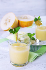 Glasses of melon cocktail on white wooden background