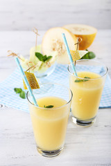 Glasses of melon cocktail on white wooden background