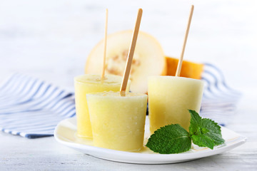 Melon ice lolly on table on light blurred background