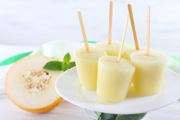 Melon ice lolly on table on light blurred background